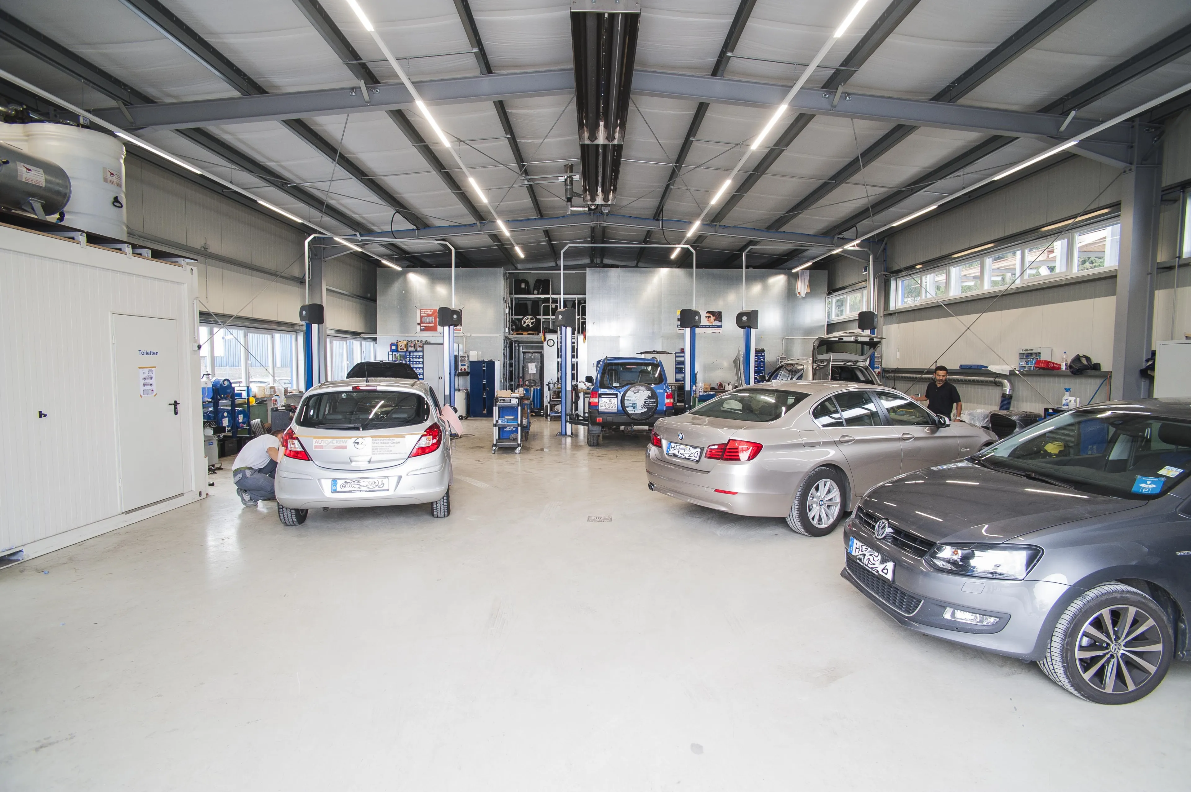Bild von der Werkstatthalle in der mehrere Fahrzeuge stehen und die Hebebühnen zu sehen sind